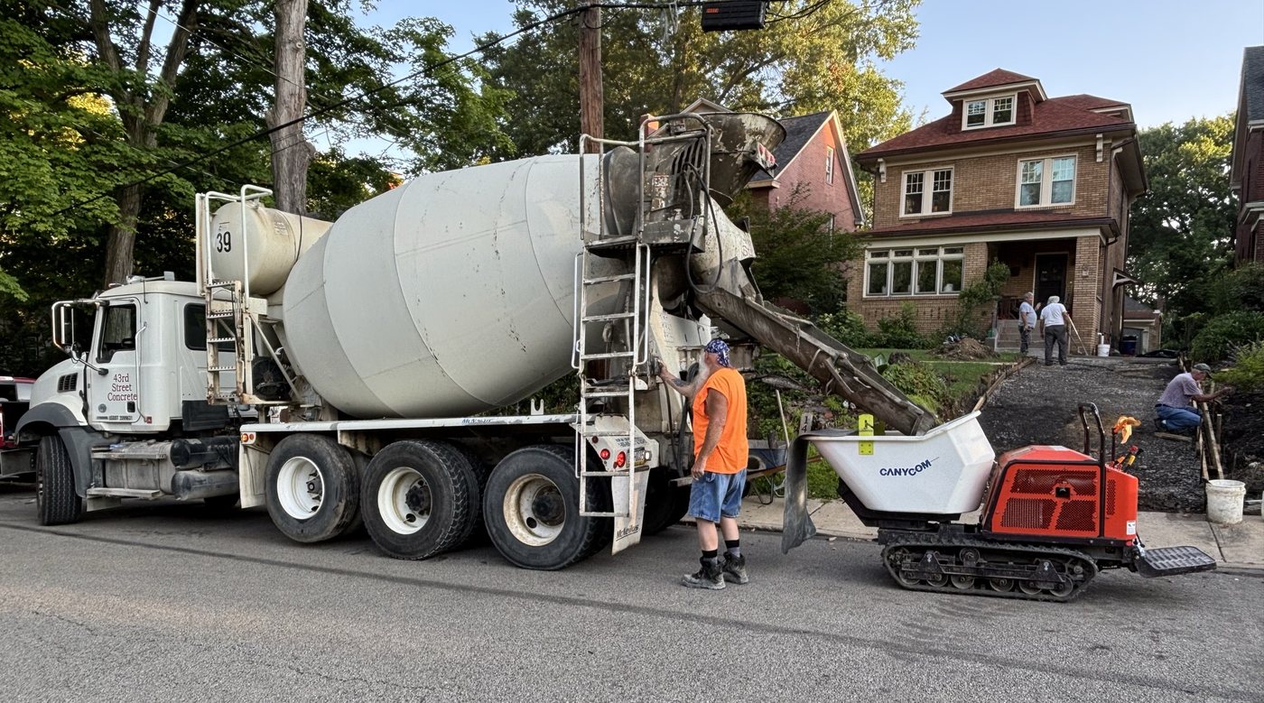 Canycom SC75 rubber-track power buggy taking concrete directly from the mixer truck chute on a Pittsburgh residential street